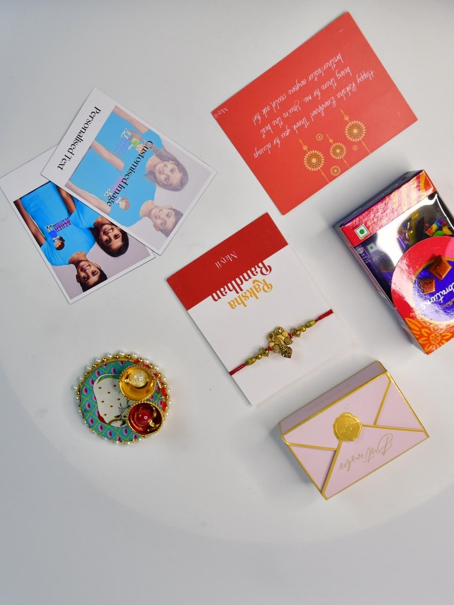 Sowpeace Exquisite Golden Ganesha Rakhi Pack of 1 with Roli Chawal Thali, Chocolates, Poloroids and Greeting card combo for Raksha Bandhan and Gifting